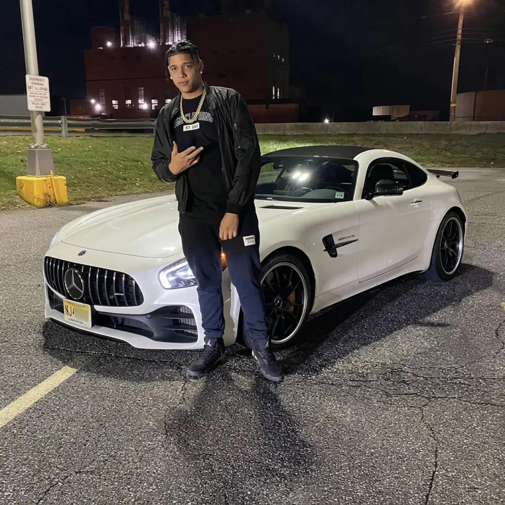 AlexOnGame92 at night beside a white sports car